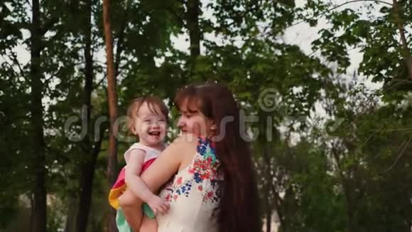年轻的妈妈在公园里玩一个小婴儿在她怀里笑着摇着视频的预览图