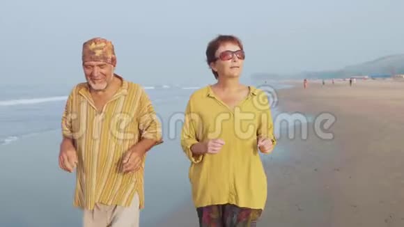 在日出时在沙滩上奔跑的老夫妇视频的预览图