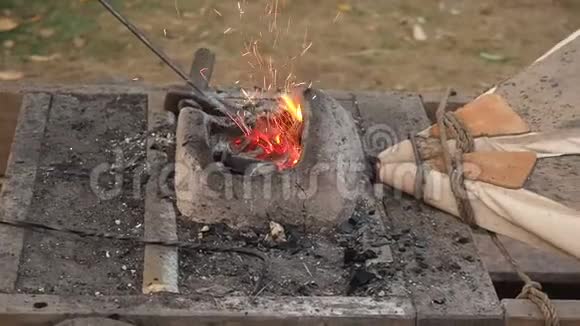 铁匠在锻造厂工作老式风箱铁匠用泥炉把钢坯放在热煤上视频的预览图