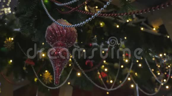挂在云杉树枝上的红色圣诞玩具在背景中失去焦点的是黄色的节日照明视频的预览图