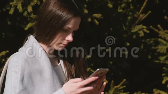 一幅美丽的黑发美女在公园的手机里读留言的肖像侧视视频的预览图