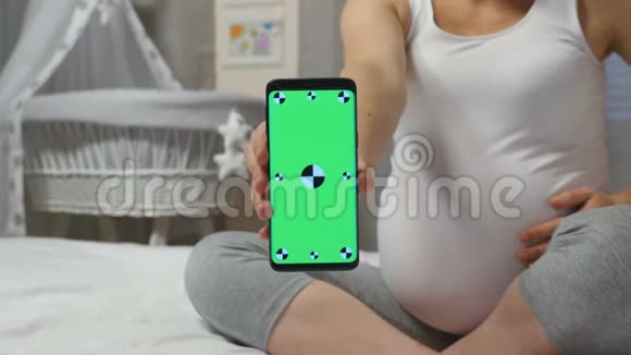 孕妇持有绿色屏幕智能手机视频的预览图