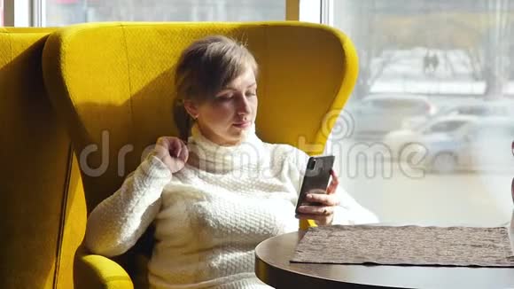漂亮的女人坐在咖啡馆里在智能手机上自拍商务午餐慢动作视频的预览图