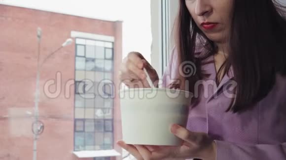 女商人坐在窗台上吃方便面靠在砖楼上视频的预览图