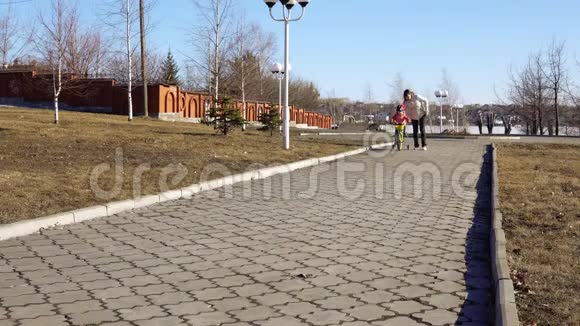 妈妈在阳光明媚的下午教女儿在公园里骑自行车视频的预览图