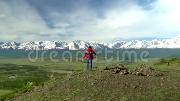 那个带着红色背包的旅行者的女人从山上站起来女人坐着看着雪山看着煤气视频的预览图