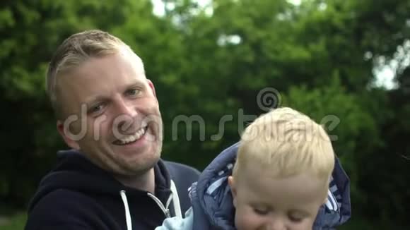 幸福的父亲和一岁可爱的儿子在森林里玩耍的肖像视频的预览图