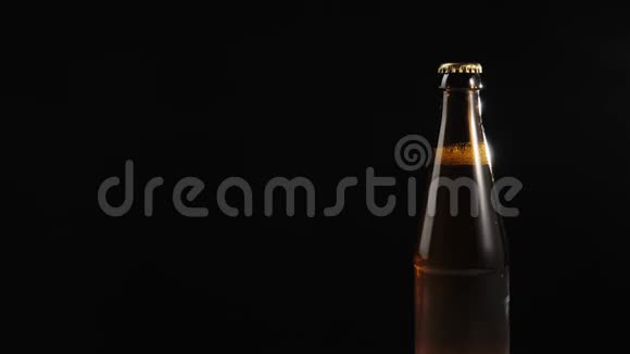 新鲜啤酒手拿一个棕色的瓶子和美味的工艺啤酒从木桌上黑色背景冷鲜啤酒视频的预览图
