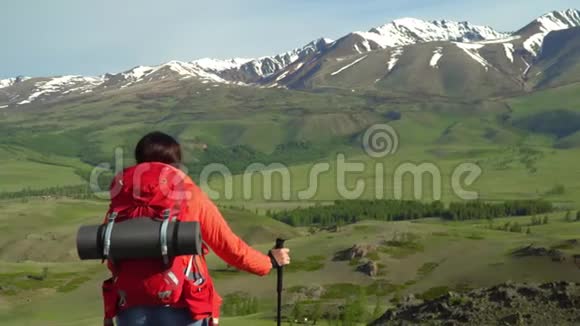 那个带着红色背包的旅行者的女人从山上站起来女人坐着看着雪山看着煤气视频的预览图