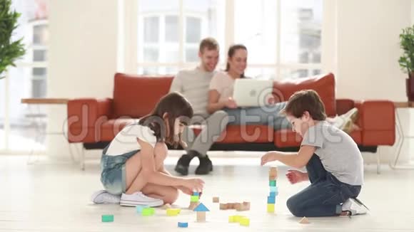 孩子们在地板上玩耍而快乐的父母则在沙发上放松视频的预览图
