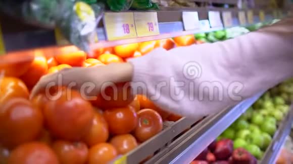 女人白色的手拿着几个五颜六色的西红柿在市场上并持有精选和购买水果或视频的预览图