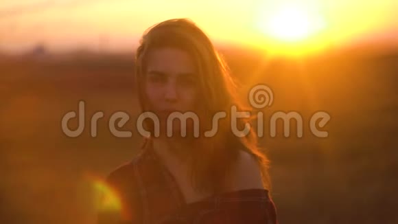特写一位迷人的年轻女子在户外微笑的肖像风中草原田野落日背景下的女人视频的预览图