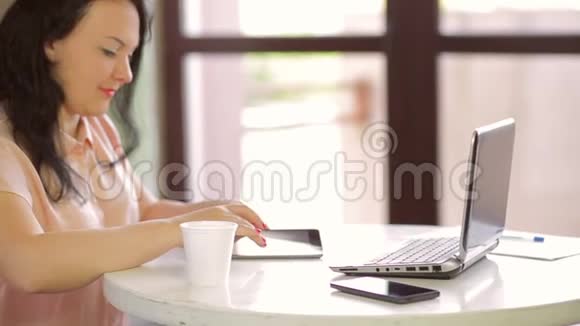 一个穿着粉红色衬衫的年轻女人的手在做平板电脑慢点视频的预览图