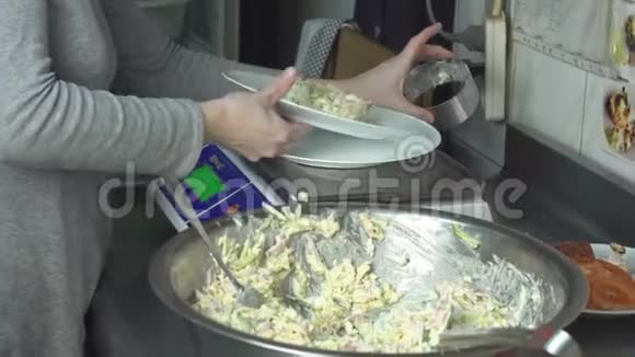 厨房里的一个厨师把沙拉的分量按克计放到桌子上秤视频的预览图