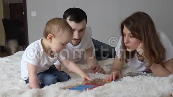 年轻的家庭在家里睡觉爸爸妈妈和他们的女儿一起玩视频的预览图