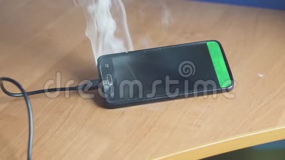 智能手机躺在桌子上吸烟和燃烧很快火就要开始了火灾危险概念电路电路视频的预览图