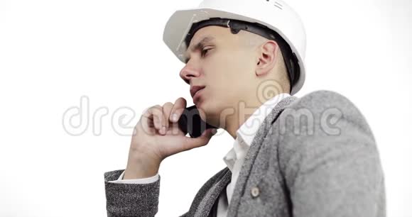 严肃的商人戴着白色建筑头盔在白色背景下的手机上交谈视频的预览图