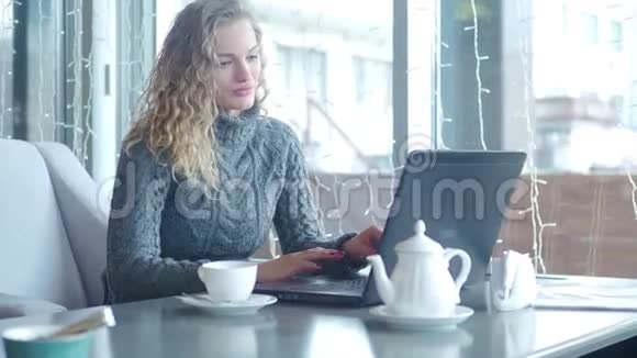 坐在咖啡馆边喝茶边用笔记本电脑打字的女商人视频的预览图