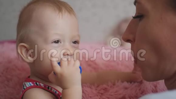 年轻的母亲和她一岁的小儿子穿着睡衣周末在卧室里放松和玩耍视频的预览图