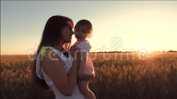 小宝宝和妈妈一起去麦田在金色夕阳的背景下欢笑慢动作视频的预览图