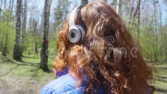 一个小女孩在公园里晨跑女孩通过耳机听音乐健康的生活方式视频的预览图