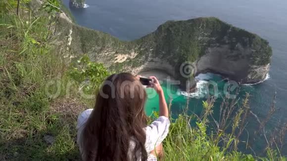 在努沙佩尼达岛拍摄海洋海岸照片的女人视频的预览图