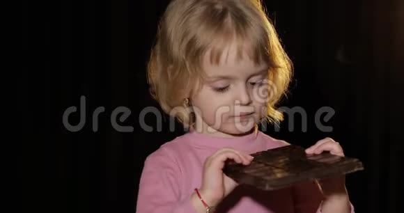 可爱的孩子吃了一大块巧克力可爱的金发女孩视频的预览图