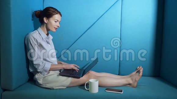 商务女性坐在沙发上在笔记本电脑上工作视频的预览图