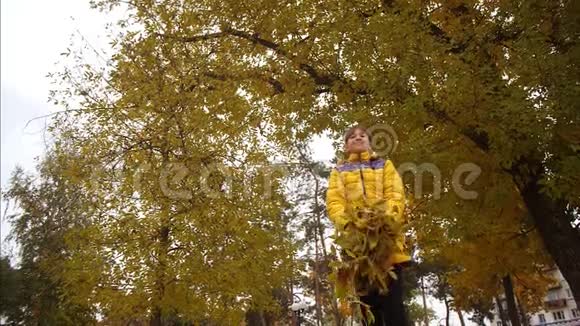 女孩把秋天的黄叶扔了起来看起来它们正在坠落慢动作视频的预览图