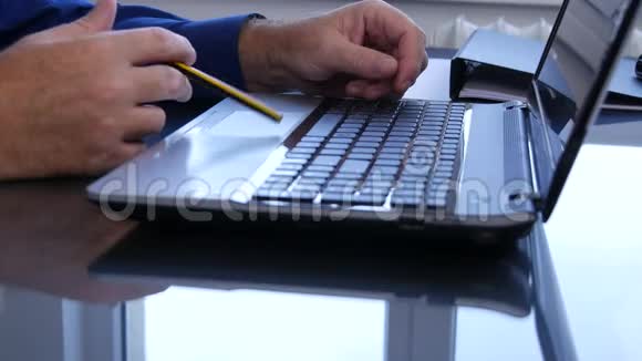 手拿铅笔在笔记本电脑键盘上紧张地玩视频的预览图