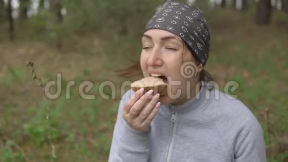 徒步中的小吃在森林里吃三明治的年轻女人视频的预览图