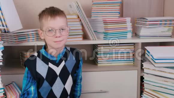 微笑的七岁男孩戴着眼镜坐在地板上的书视频的预览图