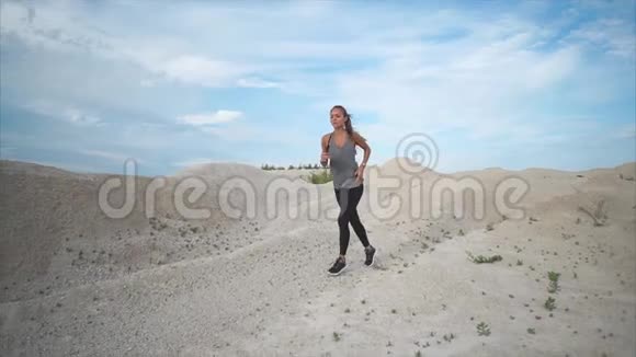 白天身材好的年轻女子沿着沙地公园奔跑视频的预览图