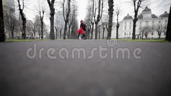 穿着天鹅绒西装的男人和穿着红色裙子的女人在空荡荡的秋天公园里跳探戈视频的预览图