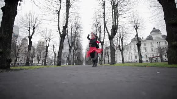 成熟的男人穿着天鹅绒夹克和穿着红色裙子和围巾的女人在街上跳舞视频的预览图