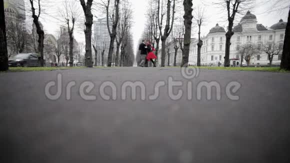 穿着天鹅绒西装的男人和穿着红色裙子的女孩在冬天在公园跳舞视频的预览图