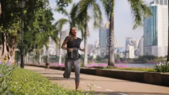 年轻混合种族运动健身女孩跑城市公园和使用智能健身跟踪手表小玩意的心脏锻炼视频的预览图