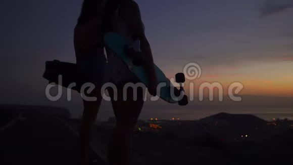 两个女孩站在路边手里拿着滑板看日落视频的预览图
