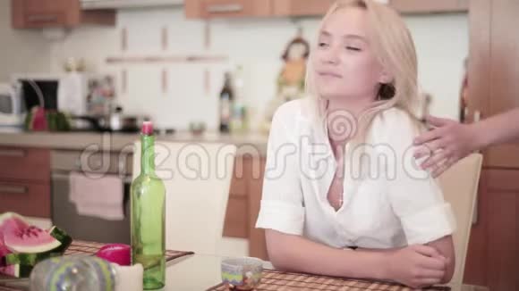 微笑的金发女人坐在厨房的桌子上年轻人加入了她的公司视频的预览图