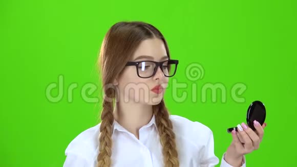 戴眼镜的女学生用刷子擦鼻子照镜子绿色屏幕视频的预览图