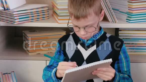 七岁戴眼镜的男孩在一本坐在书中的素描书中画了一些东西特写镜头视频的预览图