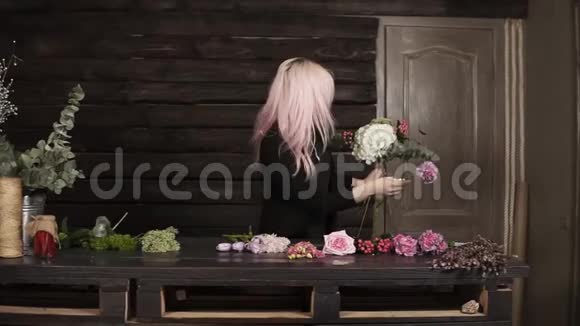 一个漂亮的女孩花店在黑暗的背景上做一个花的组成现代木制内部视频的预览图