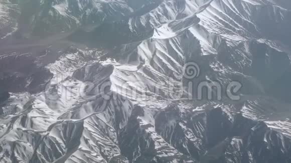 鸟瞰雪山从飞机上看山上的褶皱山顶覆盖着白雪视频的预览图