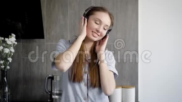 可爱的十几岁的女孩正在室内听耳机音乐视频的预览图