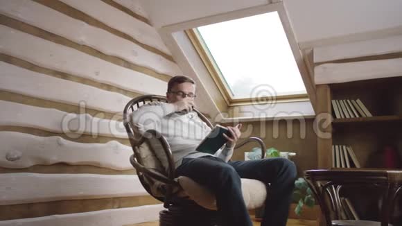 戴眼镜的成年人在阁楼上看书喝酒视频的预览图