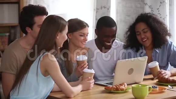快乐的年轻不同的朋友玩着看笔记本电脑上的喜剧视频的预览图