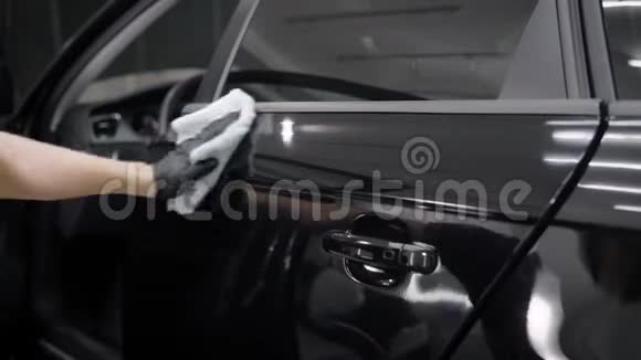 小人坐着用白毛巾擦拭黑车的门视频的预览图