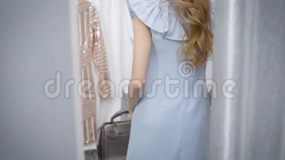 一位年轻漂亮的金发女郎照镜子一位穿着更衣室的女士她想买一件新衣服视频的预览图