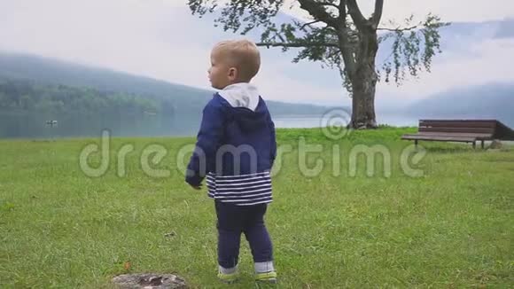 小男孩走在山湖附近在大自然中奔跑嬉戏慢动作视频的预览图
