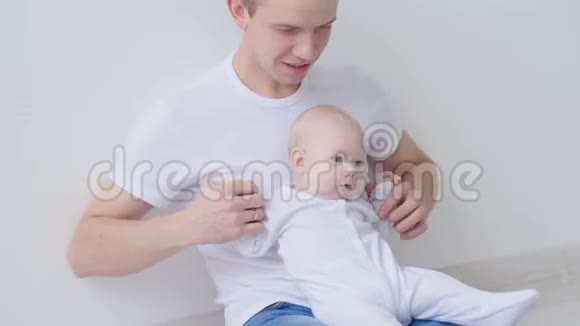年轻快乐的父亲和他的孩子在白色的室内度过时光视频的预览图